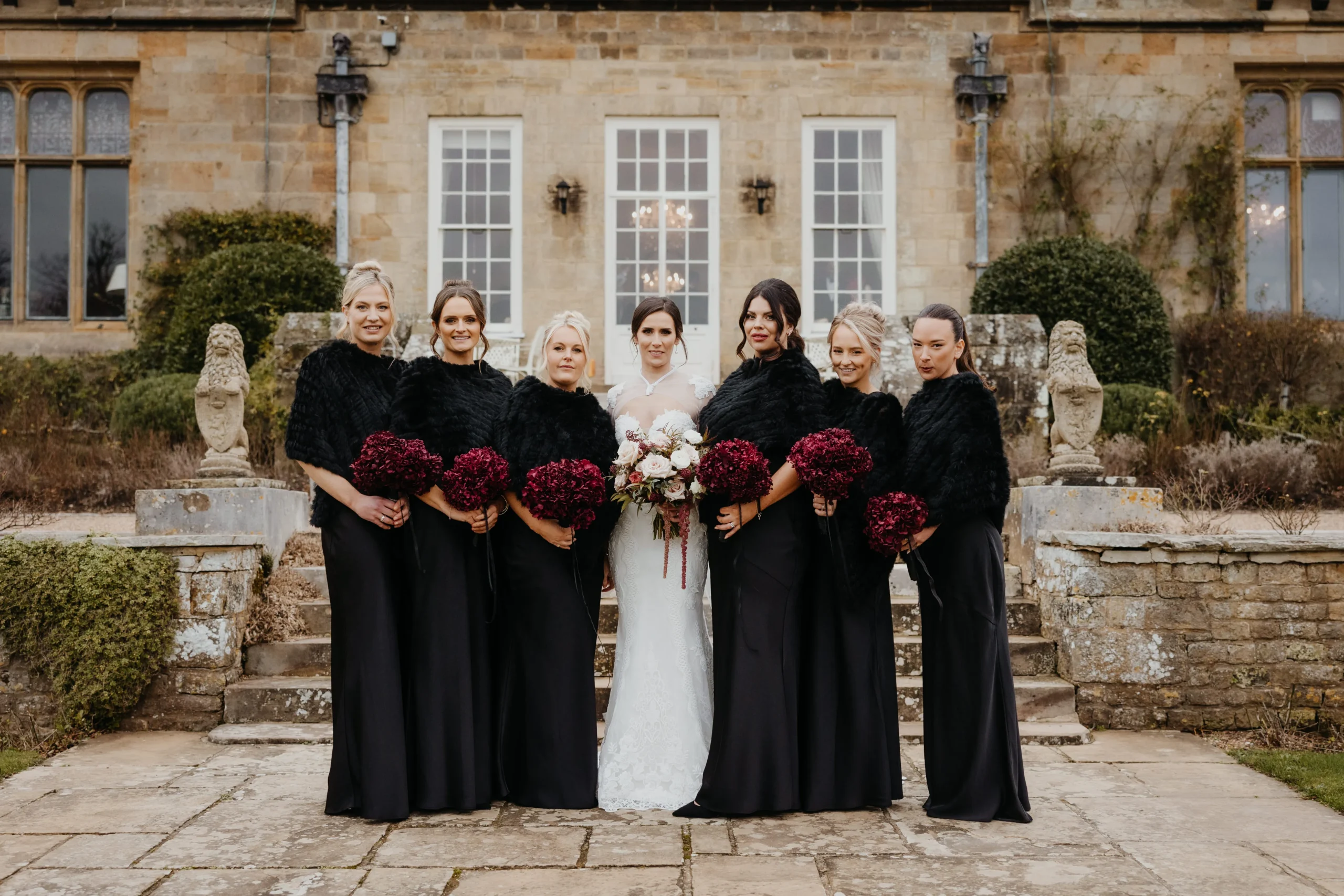 Bridesmaids carrying winter wedding bouquets at Cowdray House
