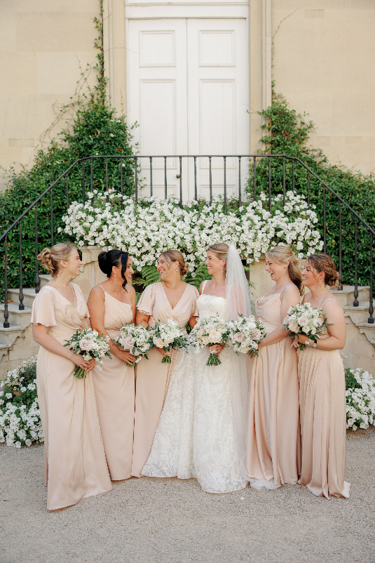 Olivia with her bridesmaids holding matching blush and ivory bouquets